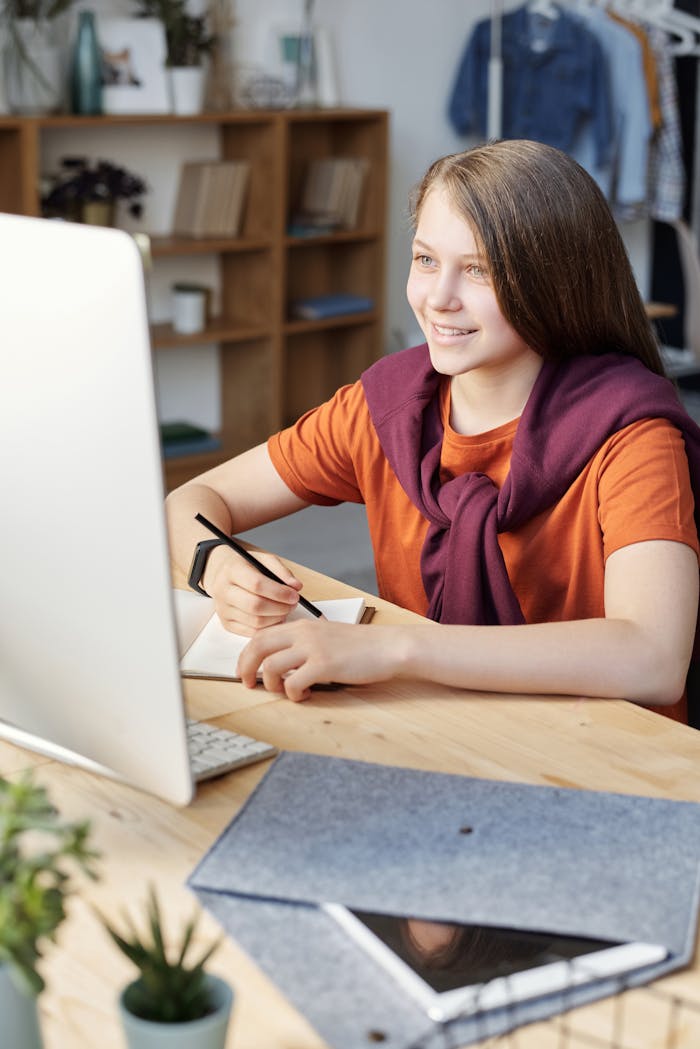 Woman in Orange Shirt Writing on White Paper